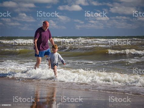 Happy Grandpa Playing With Grandson On The Beach In Seawater Delight