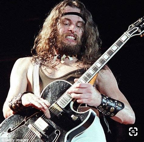 A Man With Long Hair Playing An Electric Guitar