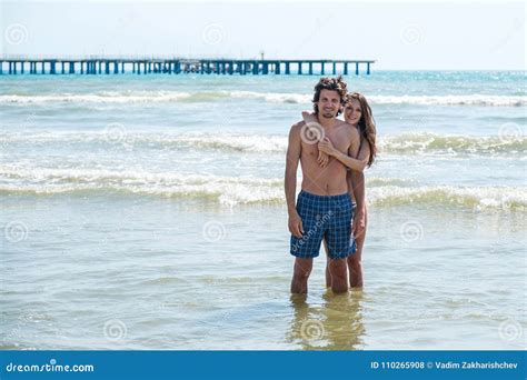 Brunette Woman In Bikini Hugs A Beautiful Long Haired Man From Behind