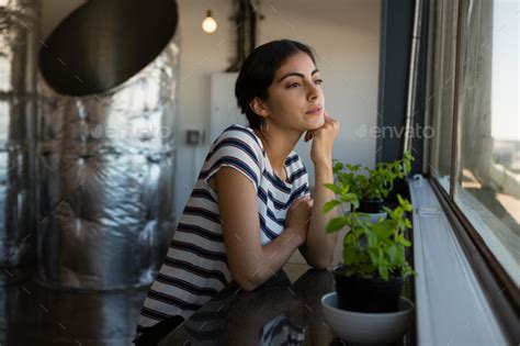 Thoughtful Young Woman Looking Through Window At Office Stock Photo By