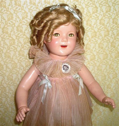 A Doll With Blonde Hair Wearing A Brown Dress