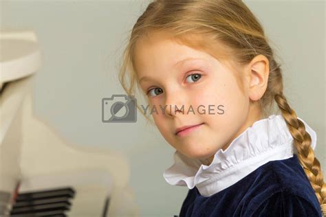 Beautiful Blonde Little Girl Playing Piano And Looking At Camera By