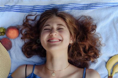 Smiling Young Woman Lying On Her Back On A Blanket And Relaxing Stock