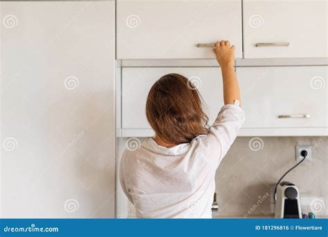 Back View Of Woman Putting Or Taking Clean Plate On The Shelf In
