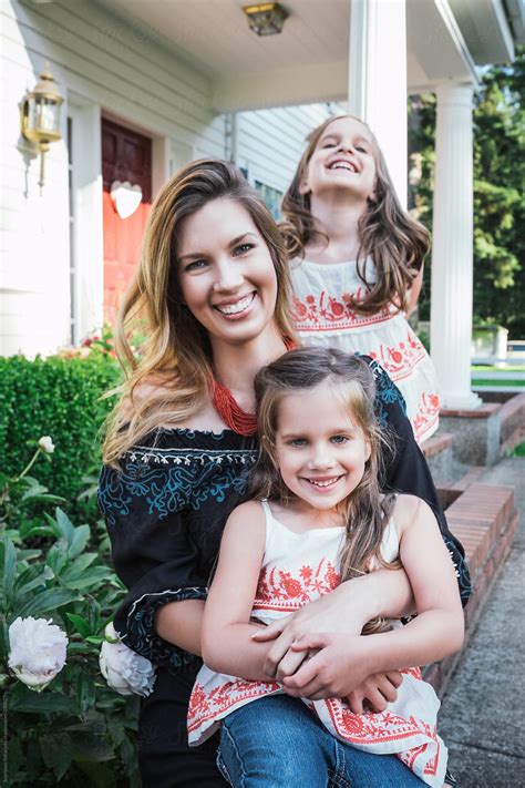Portrait Of A Happy Mother And Twin Daughters In Front Of Their Home
