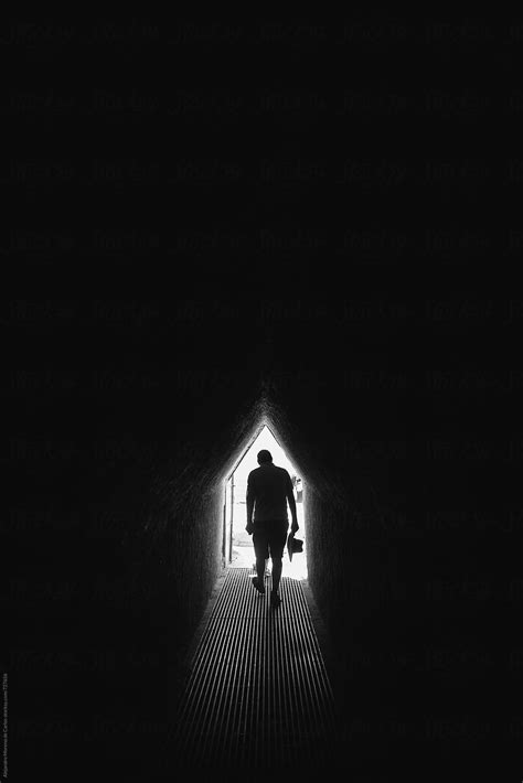 Silhouette Of A Man Walking Through An Underground Tunnel In Black And