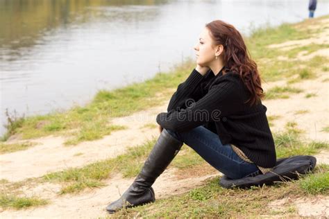 Mujer Joven Sola Que Se Sienta En Una Orilla Del Lago Foto De Archivo