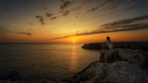 Photo Of Person Sitting On Rock During Sunset · Free Stock Photo
