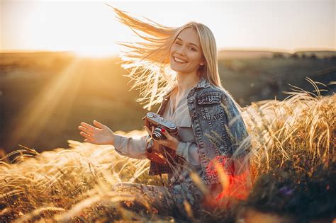 Фото Симпатичная девушка блондинка с фотоаппаратом стоит в поле