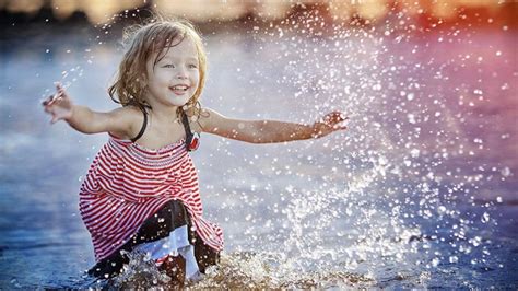 Cute Little Girl Is Playing On Body Of Water During Daytime Wearing Red