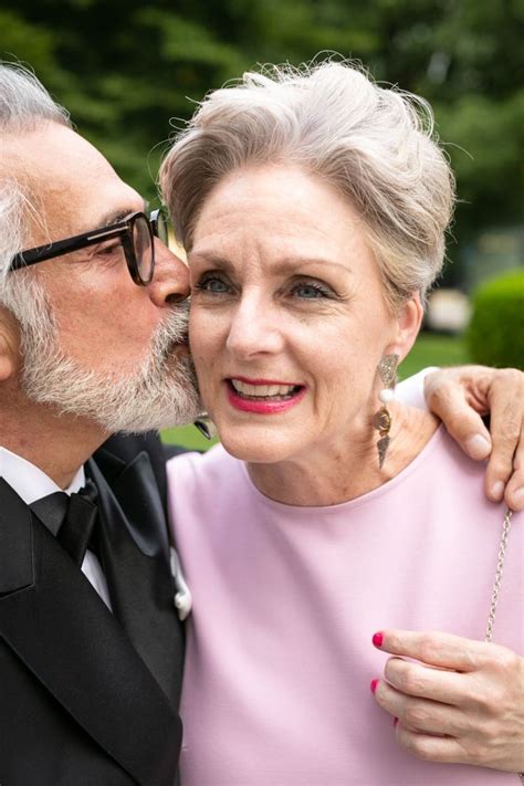 An Older Couple Kissing Each Other While Wearing Tuxedos