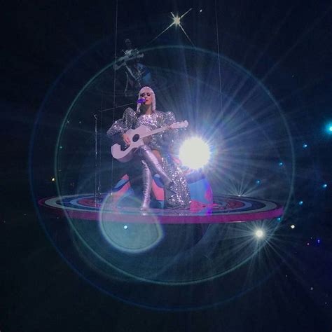 Lady In Silver Outfit Playing Guitar On Stage With Bright Lights And