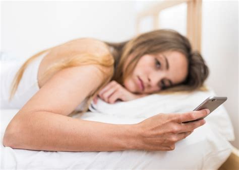 Free Photo Young Woman Lying On Bed Using Mobile Phone