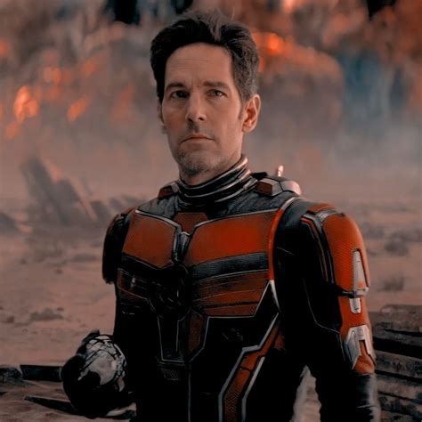 A Man Dressed As Ant Man Standing In Front Of A Pile Of Wood And Logs