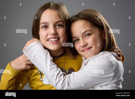 Identical Twin Girls Sisters Are Posing For The Camera Happy Twin Sisters Looking At The Camera