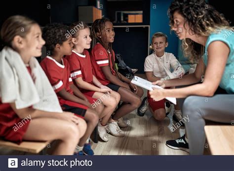 The Kids Soccer Team Talking To Their Coach In A Locker Room Stock