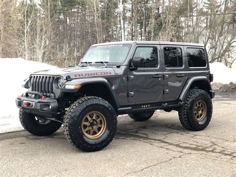 A Black Jeep With Gold Rims Parked On The Side Of A Road In Front Of