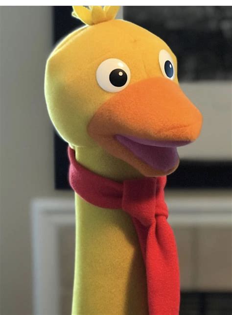 A Stuffed Duck With A Red Scarf Around Its Neck And Eyes Looking At