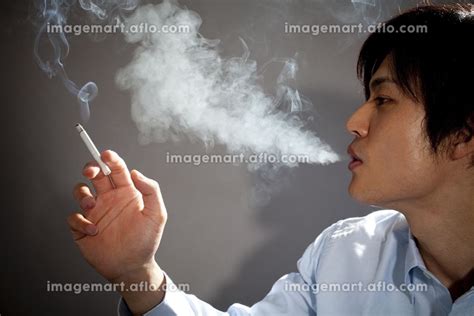 タバコの煙を吐くビジネスマンの写真素材 [23992647] イメージマート