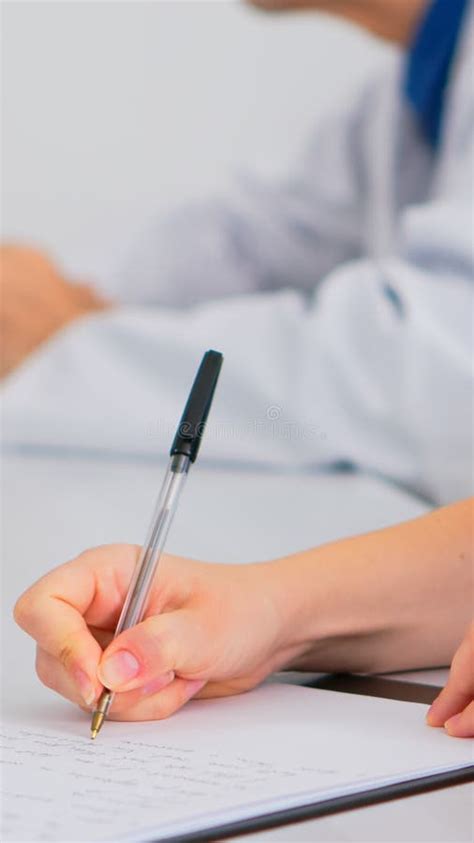 Close Up Of Nurse Writing On Clipboard During Medical Meeting Stock