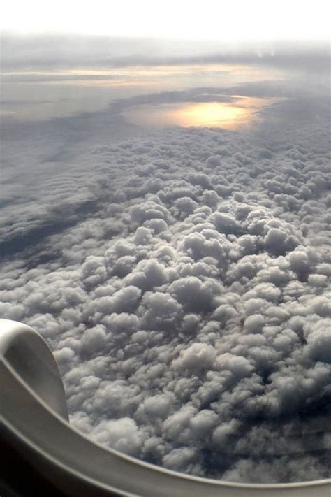 The View From An Airplane Window Shows Clouds In The Sky And Sun
