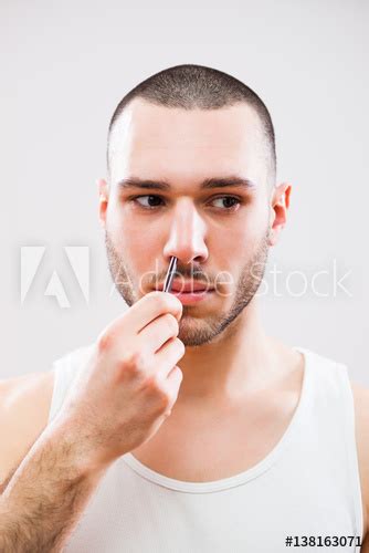 Young Man Is Plucking Nose Hair With Tweezers Kaufen Sie Dieses Foto
