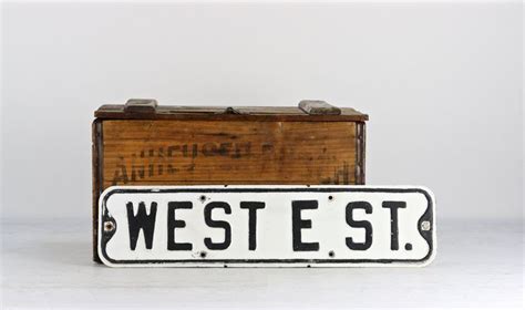 An Old West Street Sign Sitting On Top Of A Wooden Box Next To A Piece