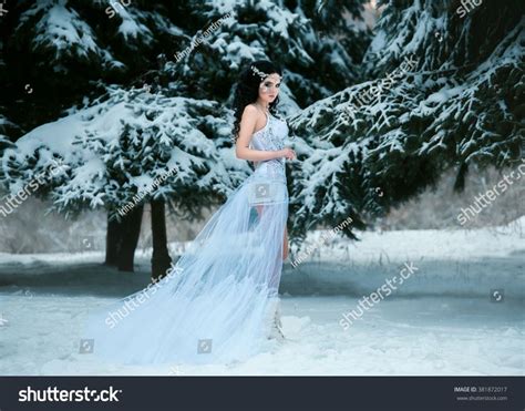 Luxurious Brunette In A White Dress Standing In A Snowy Forest Snow