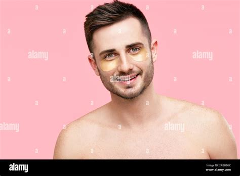Portrait Of Smiling Handsome Man With Golden Eye Patches On Pink