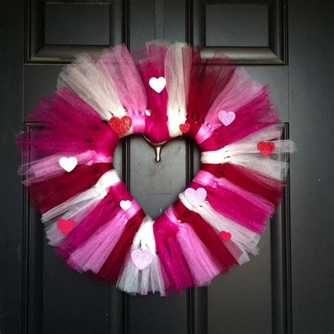 A Pink And White Heart Shaped Tulle Wreath Hanging On A Black Door With