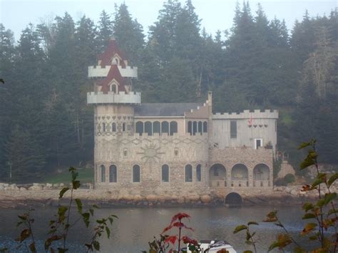 An Old Castle Sitting On Top Of A Lake Surrounded By Trees In The Foggy Day