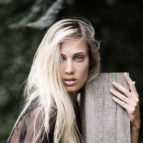A Woman With Long Blonde Hair Leaning Against A Wooden Fence And