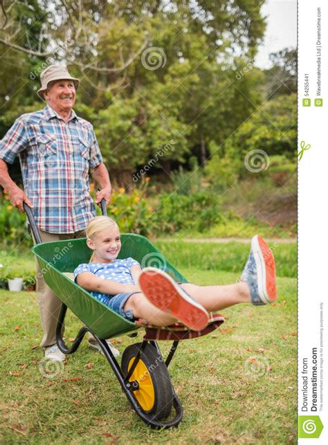 Happy Grandfather And His Granddaughter With A Wheelbarrow Stock Image