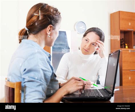 Mature Woman Answer Questions Of Outreach Worker With Laptop In Home Or