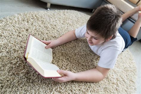 Boy Reading A Book While Lying On Carpet In The Room Stock Image