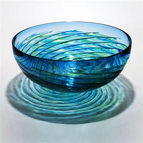 A Blue Glass Bowl Sitting On Top Of A White Table Next To A Water Drop