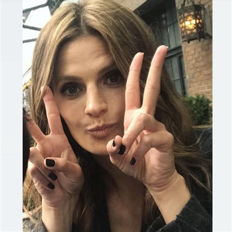 A Woman Is Making The Peace Sign With Her Hands And Holding Up Two