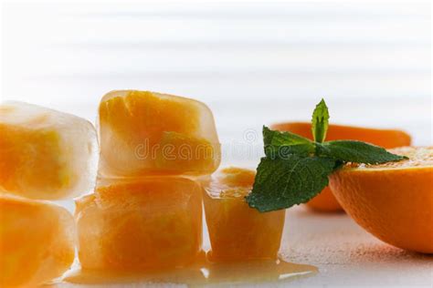 Orange Fruit Frozen In Ice Cubes And Mint Leaves On White Stock Photo