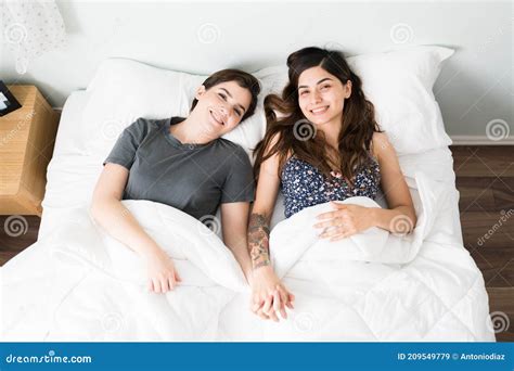 Top View Of Happy LGBT Girlfriends In Bed Smiling At The Camera Stock