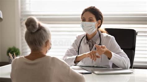 Female Doctor In Facemask Consult Mature Patient Stock Photo Image Of