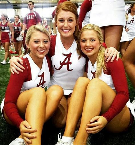 Three Women In Red And White Uniforms Sitting On The Ground With Their