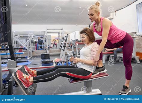 Mature Woman Doing Sport Exercises With Personal Trainer At Gym Female