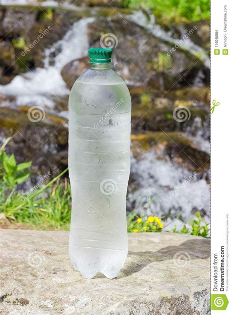Bottle Of Cold Drinking Water Against Of Mountain Stream Closeup Stock