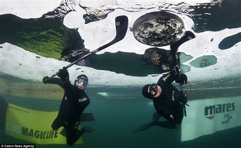 Underwater Ice Hockey Divers Play In Water Beneath Layer Of Ice In