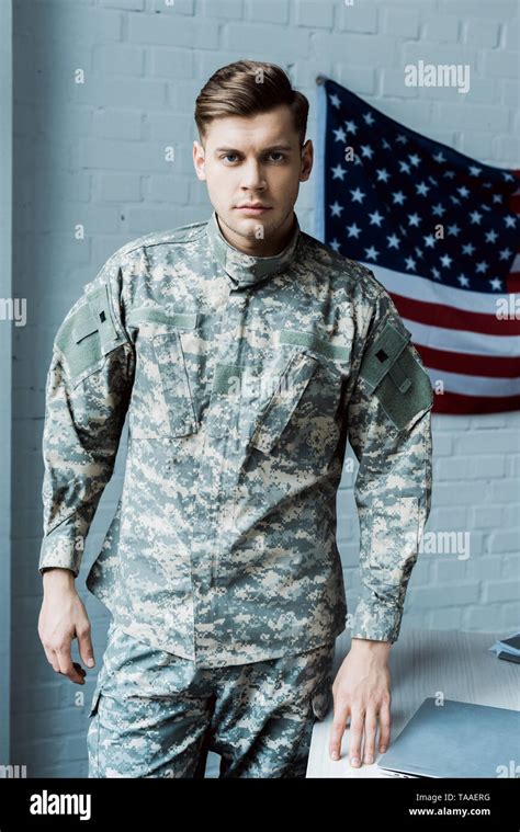 Handsome Man In Military Uniform Standing Near Table In Office Stock