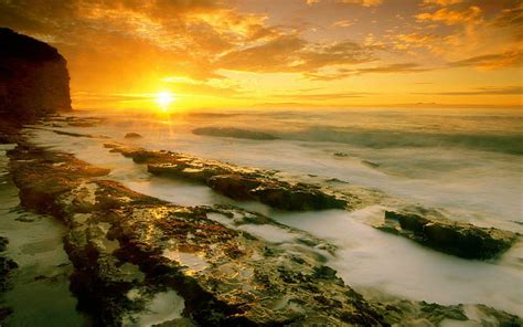 Misty Sunset Over The Rocky Shore Golden Hour View On The Ocean