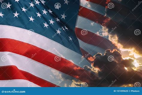 American Flag Waving In Cloudy Sky And Bright Sunrise Over The Horizon