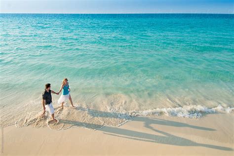 Aerial View Of Romantic Couple Walking Along Tropical Caribbean Beach