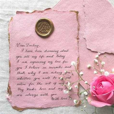 A Pink Rose Sitting On Top Of A Piece Of Paper Next To A Wax Stamp