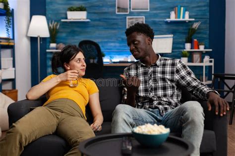 Cheerful Interracial Couple Sitting On Sofa In Living Room Stock Image Image Of Glass
